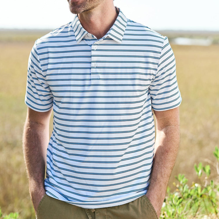Man wearing a striped polo shirt standing in an open field